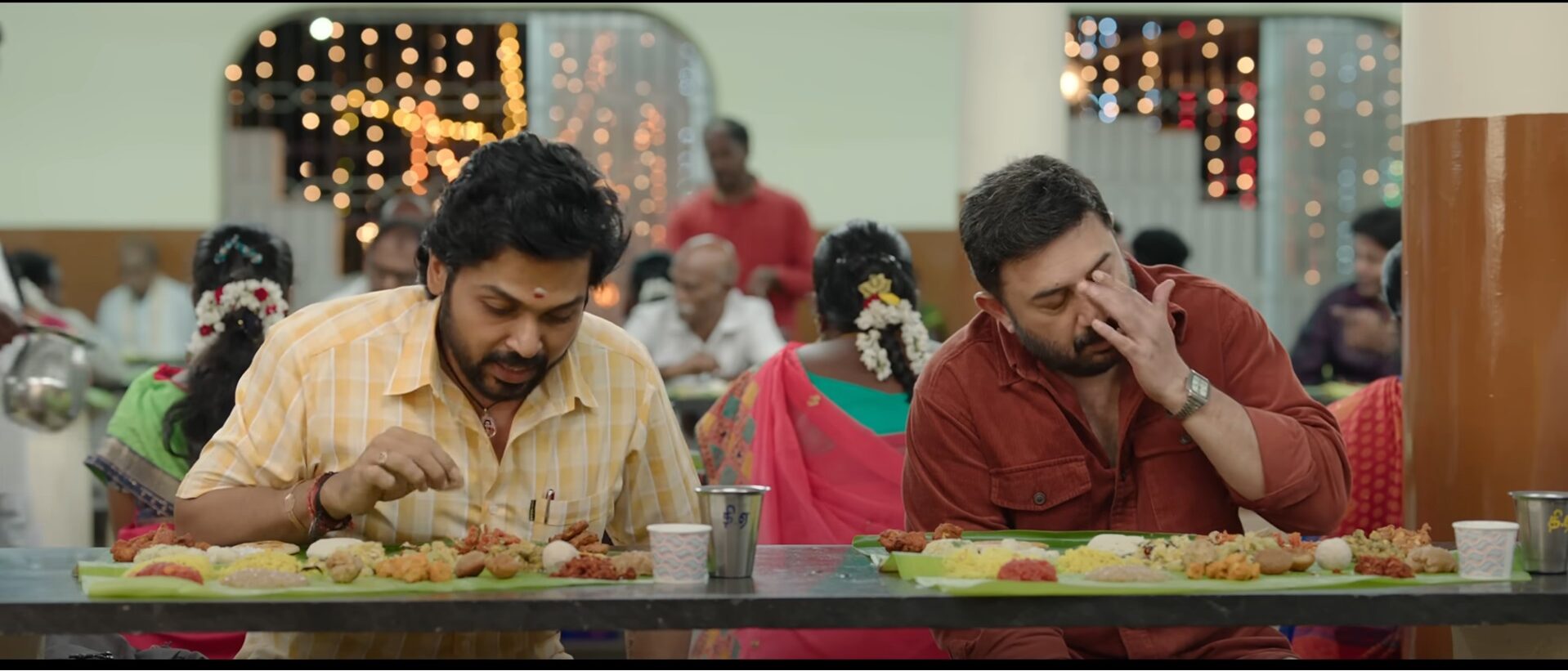 A scene from Meiyazhagan where Arvindswami and Karthi show different expressions for the food in front of them